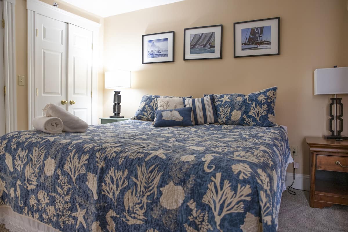 A bedroom with a large bed, a nightstand, a lamp, and a door.