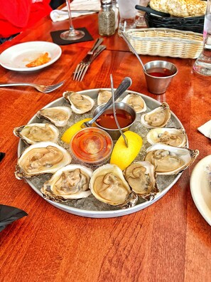 A plate of oysters with lemon wedges and a dipping sauce on a wooden table. - The Winthrop Arms Hotel And Restaurant (Winthrop)