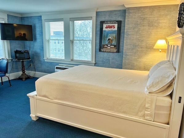A hotel room with a large bed, a television, a poster on the wall, and a window with blinds. - The Winthrop Arms Hotel And Restaurant (Winthrop)