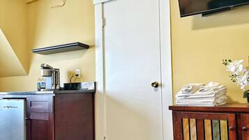 Cocina compacta con refrigerador, estufa y televisor de pantalla plana montado en la pared.