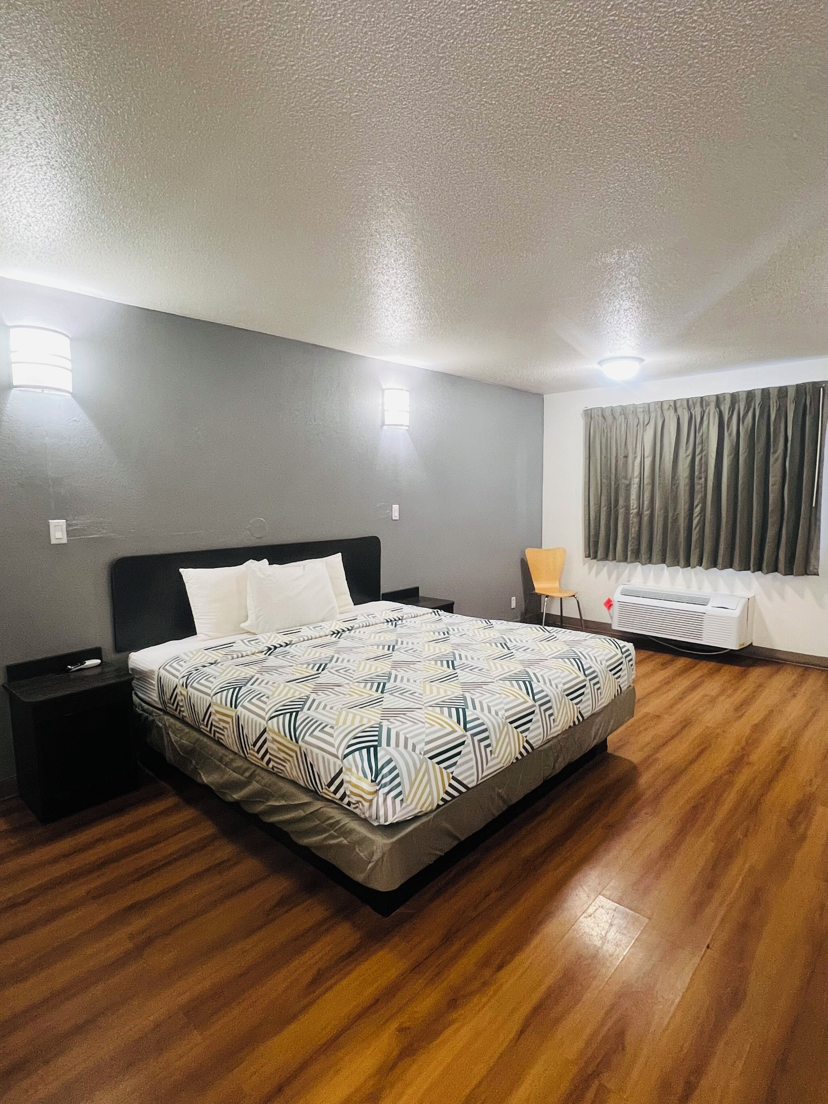 A bedroom with a bed, nightstands, a window with curtains, and a radiator.