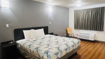 A bedroom with a bed, nightstands, a window with curtains, and a radiator.