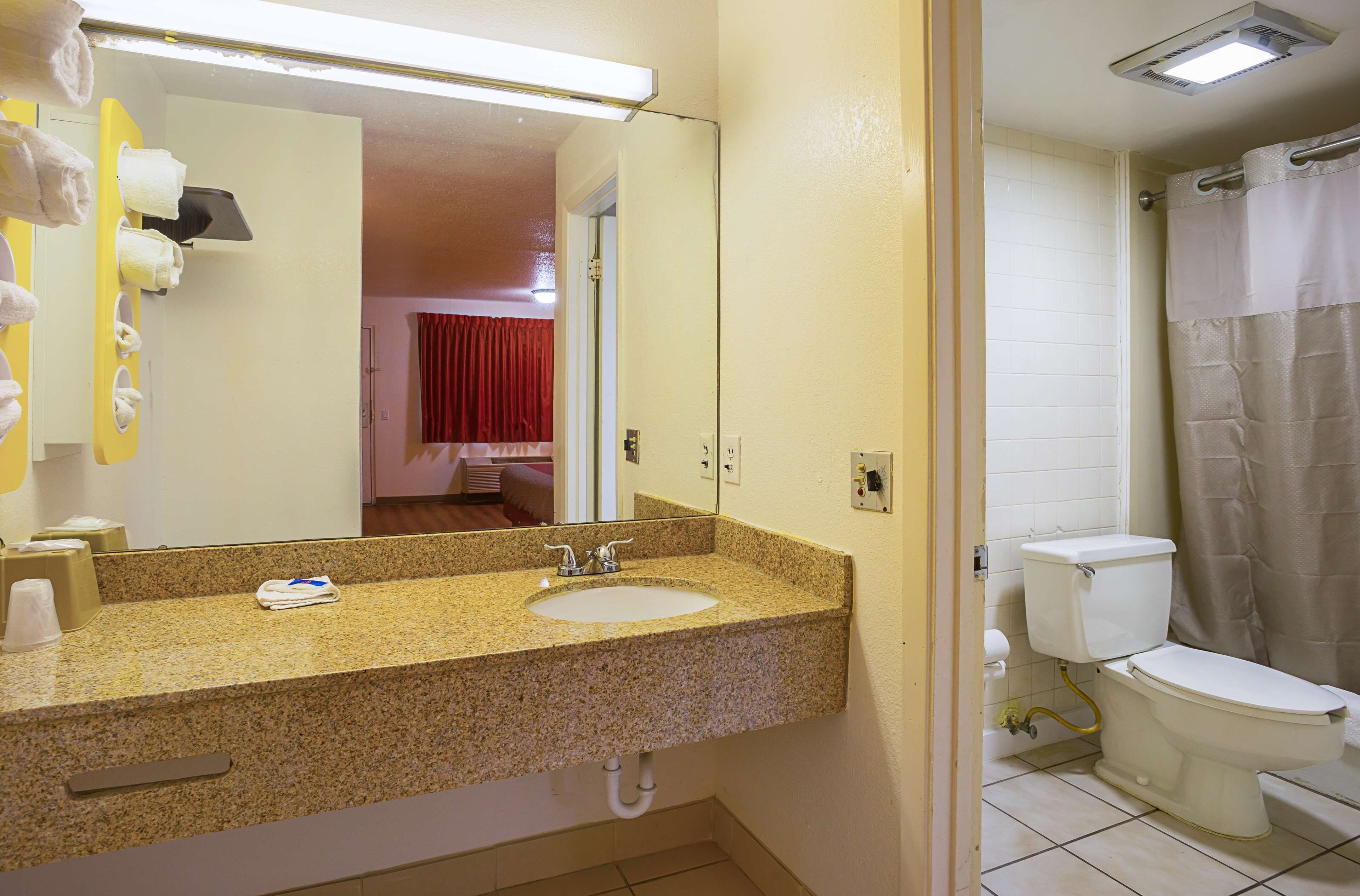 A bathroom with a granite countertop sink, a mirror, a toilet, and a shower curtain.
