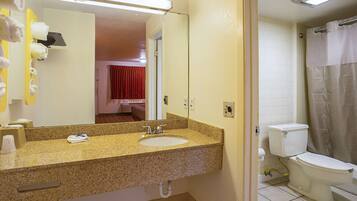 A bathroom with a granite countertop sink, a mirror, a toilet, and a shower curtain.