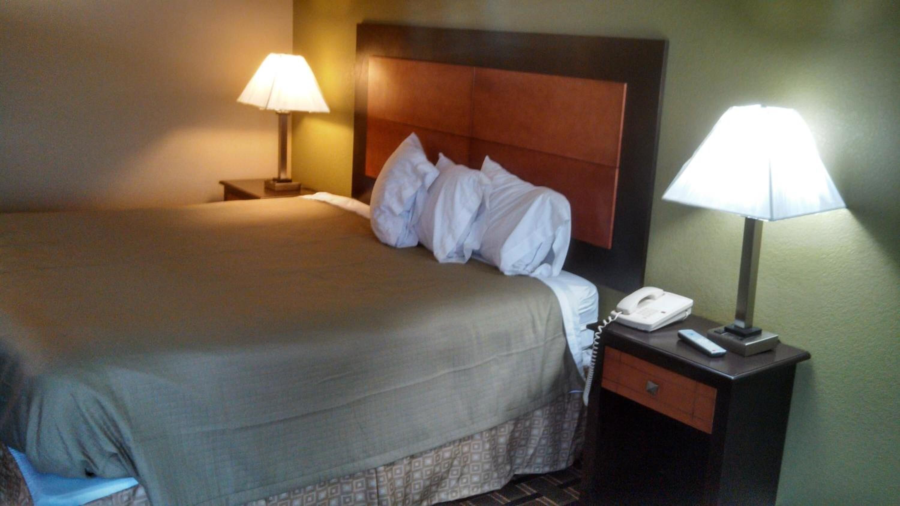 A hotel room with a bed, two bedside lamps, a telephone, and a nightstand.