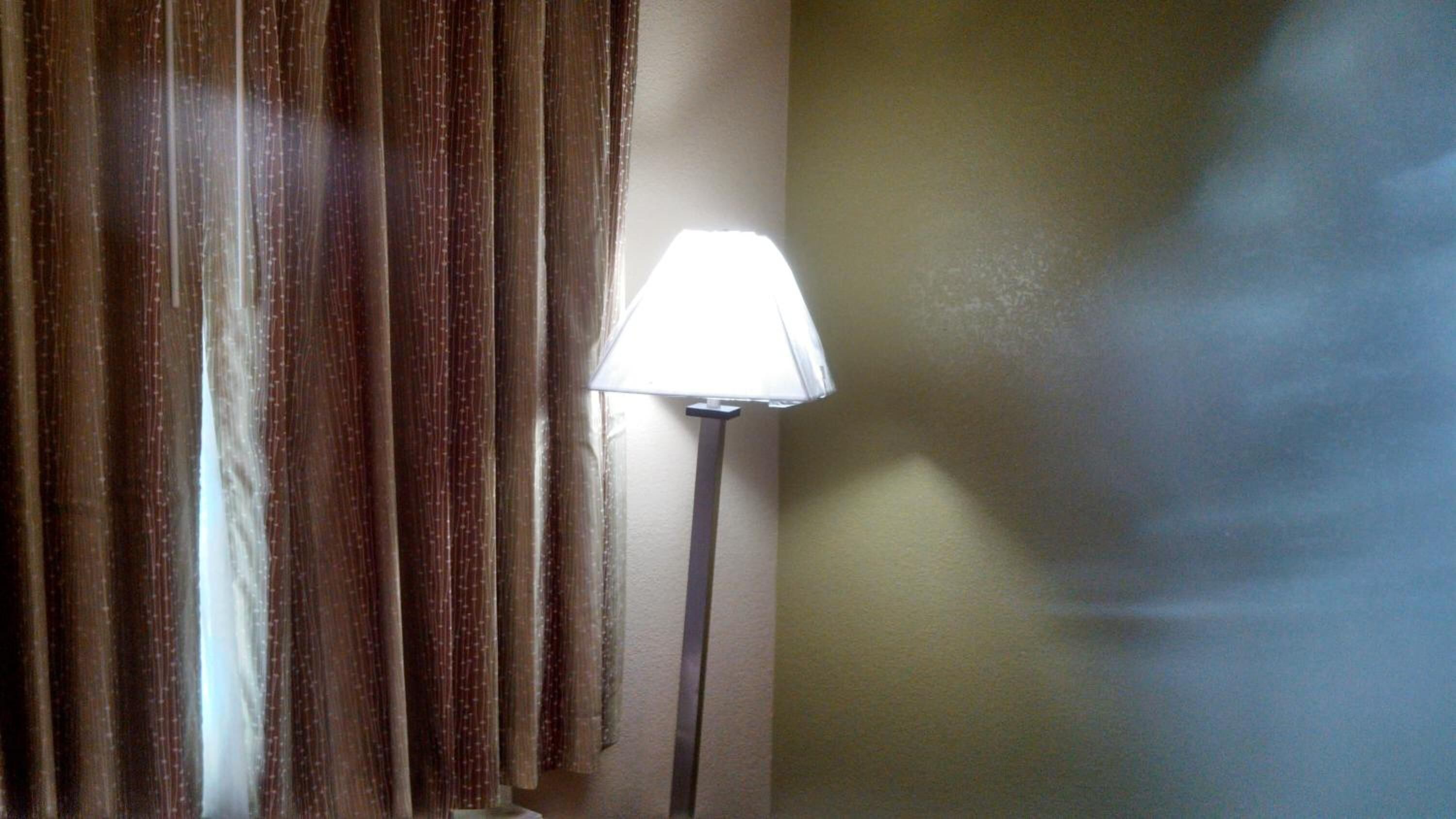 A room with a floor lamp, a curtain, and a wall.