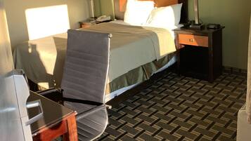 Une chambre d’hôtel avec un lit, deux tables de chevet avec des lampes, une chaise et un sol recouvert de moquette.