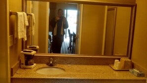 A bathroom with a sink, mirror, and towel rack.