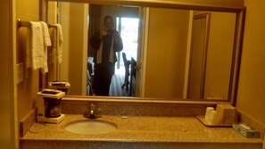 A bathroom with a sink, mirror, and towel rack.