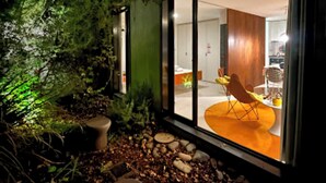 Una casa moderna con fachada de vidrio, rodeada de zona boscosa.