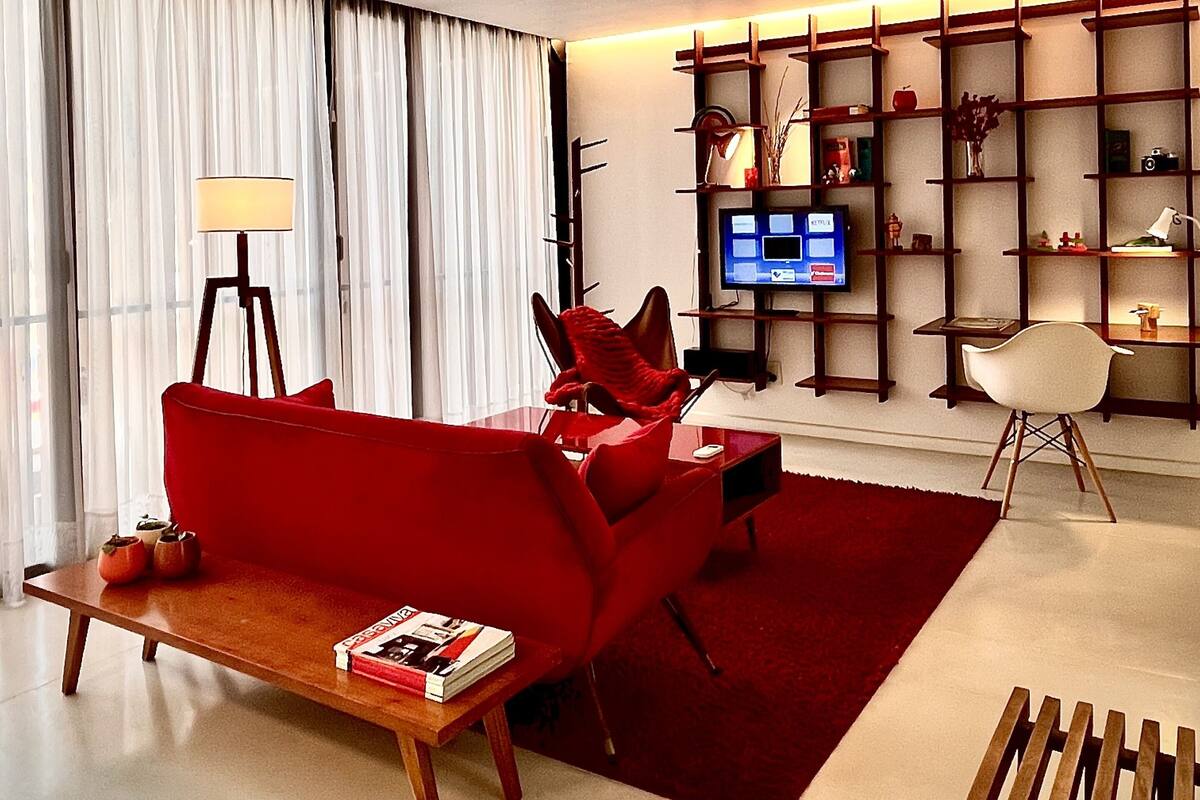 A modern living room with a red sofa, a wooden coffee table, a TV, and a bookshelf.