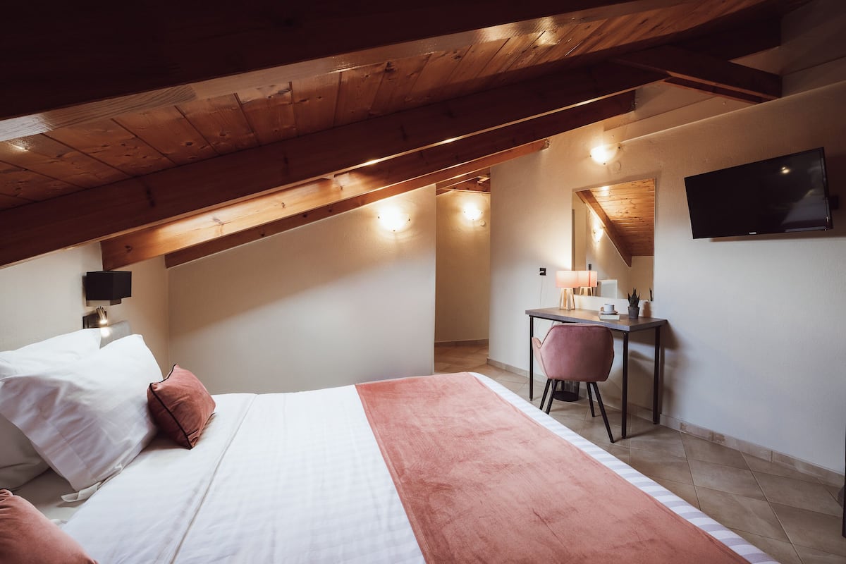 Ein Schlafzimmer mit einem Bett, einem Schreibtisch, einem Stuhl, einem Fernseher und einem kleinen Tisch mit einer Lampe.
