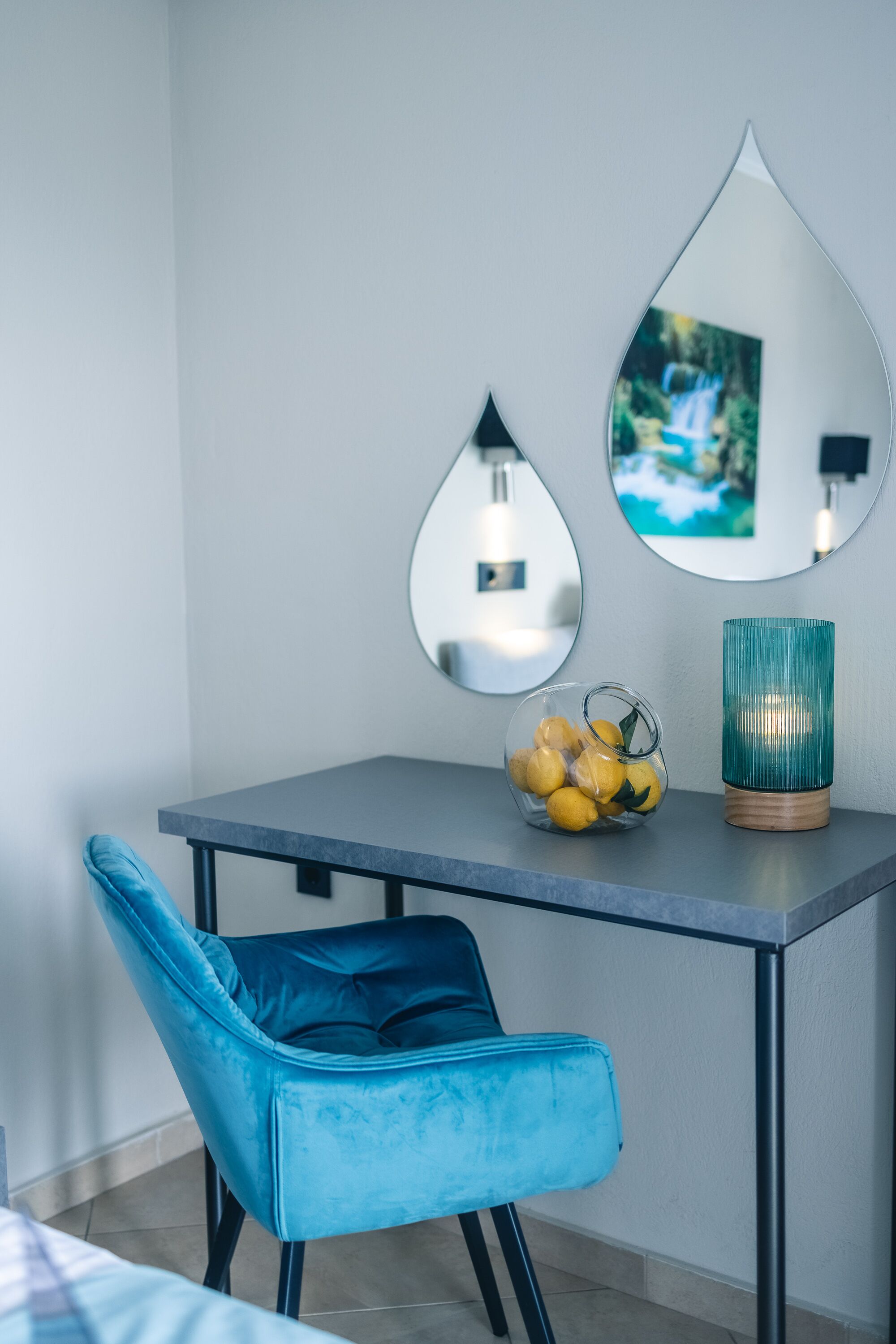 A modern room with a grey table, a blue chair, and decorative mirrors.