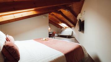 A bedroom with a bed, a chair, a table, and a ceiling fan.