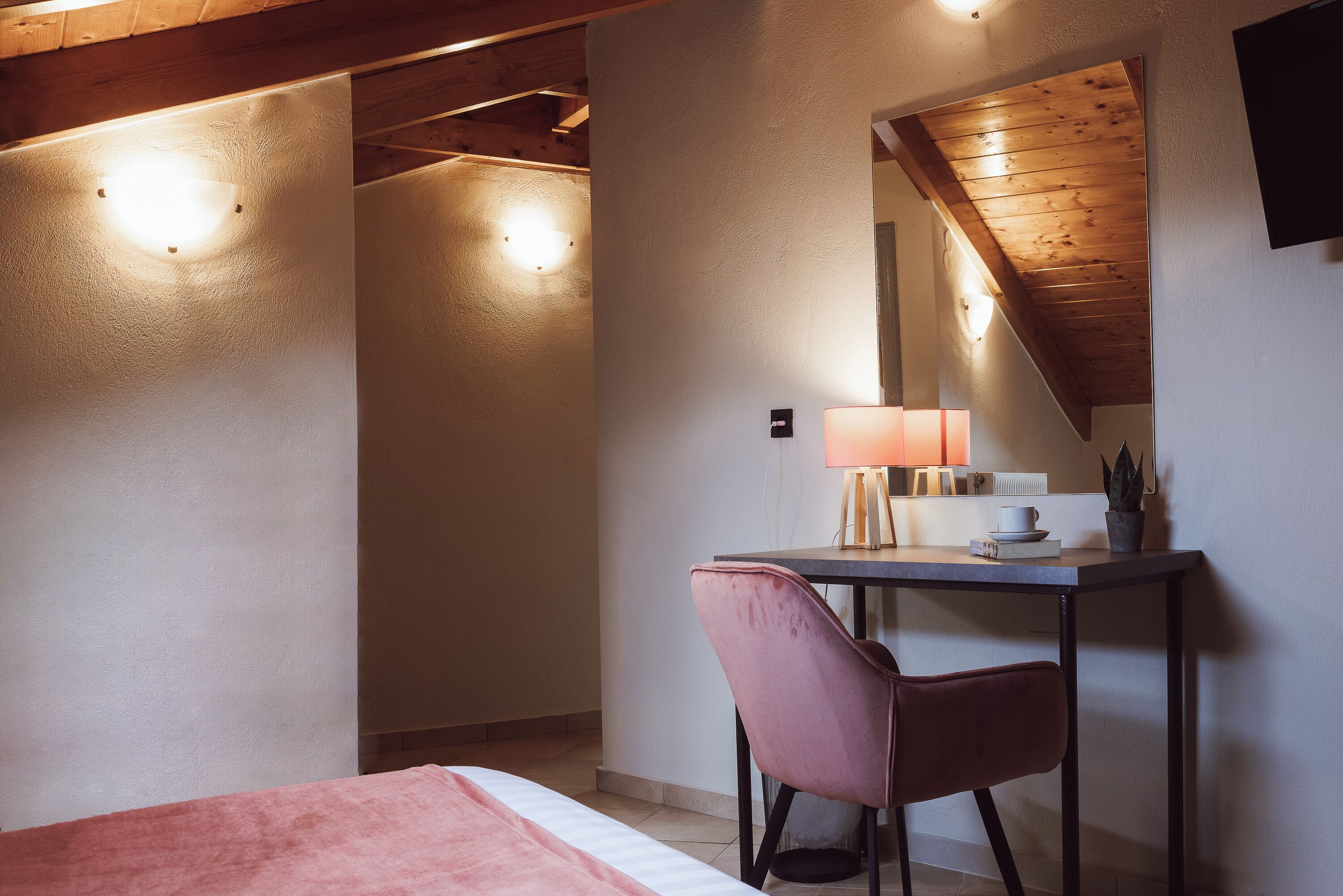 Ein Schlafzimmer mit Bett, Schreibtisch, Stuhl, Lampe und Spiegel.