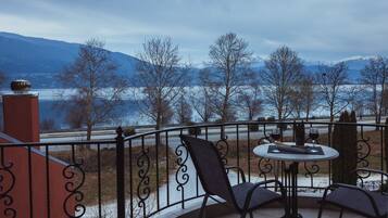 A balcony with a table and chairs, overlooking a snowy landscape and a body of water.