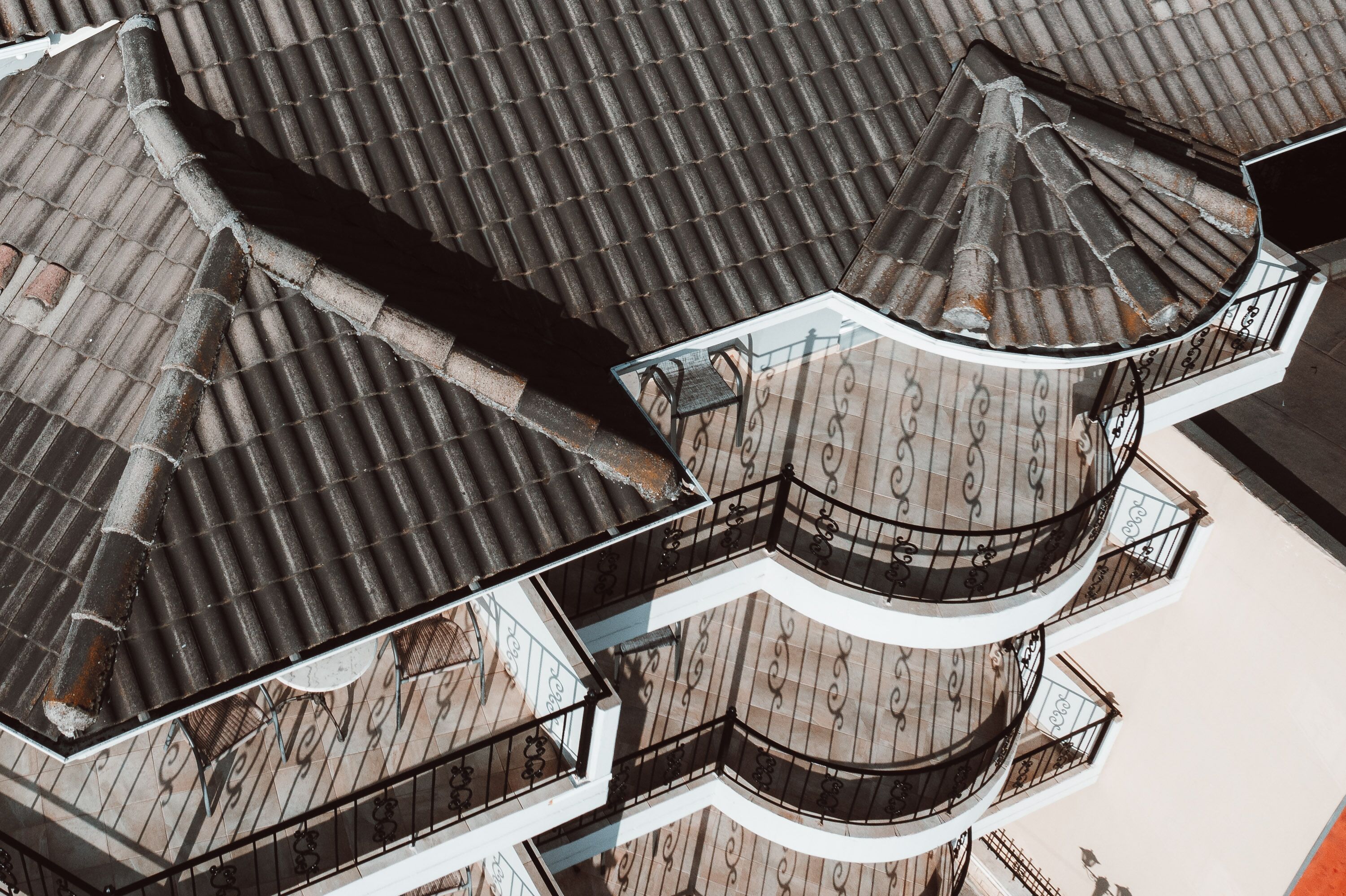 Een meerlaags gebouw met een pannendak en een rond balkon met versierde hekwerken.