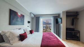 Een hotelkamer met een groot bed, een wandgemonteerde televisie en een balkon met uitzicht op bergen.