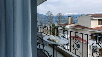 A balcony with a table and chairs, overlooking a mountain range.