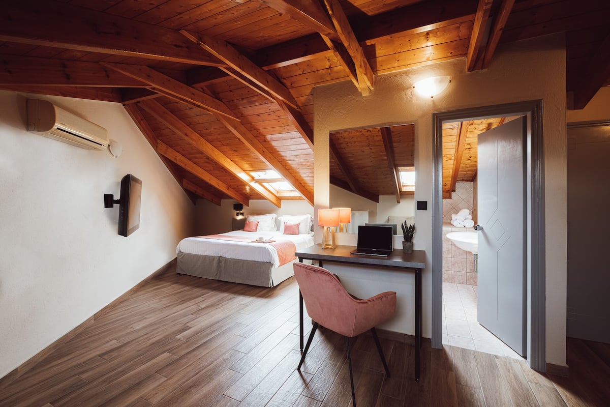 Ein Schlafzimmer mit Bett, Schreibtisch, Stuhl und einer offenen Tür zu einem Badezimmer.