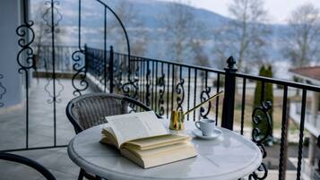 Una mesa redonda con un libro, una taza y un objeto dorado en un balcón con vista a las montañas.