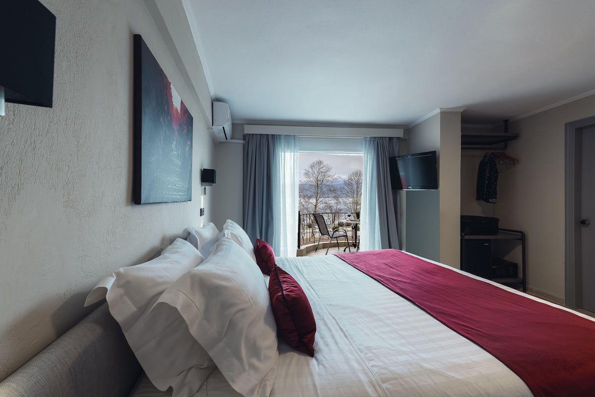 Ein Hotelzimmer mit einem großen Bett, Blick ins Freie, einem Wandfernseher und einem Kleiderschrank.