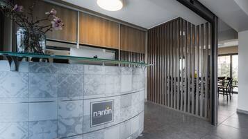 A reception area with a marble counter, a glass vase with flowers, and a wooden panel wall.