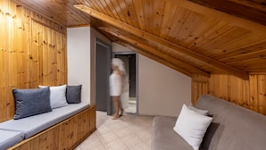 Una habitación con paneles de madera, un sofá con cojines y suelo de baldosas.