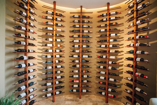 A wine cellar with multiple wooden racks holding numerous bottles. - Royal Palm Galapagos, Curio Collection Hotel by Hilton (Santa Rosa)