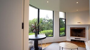 A modern living room with a fireplace, large windows, and a dining area.