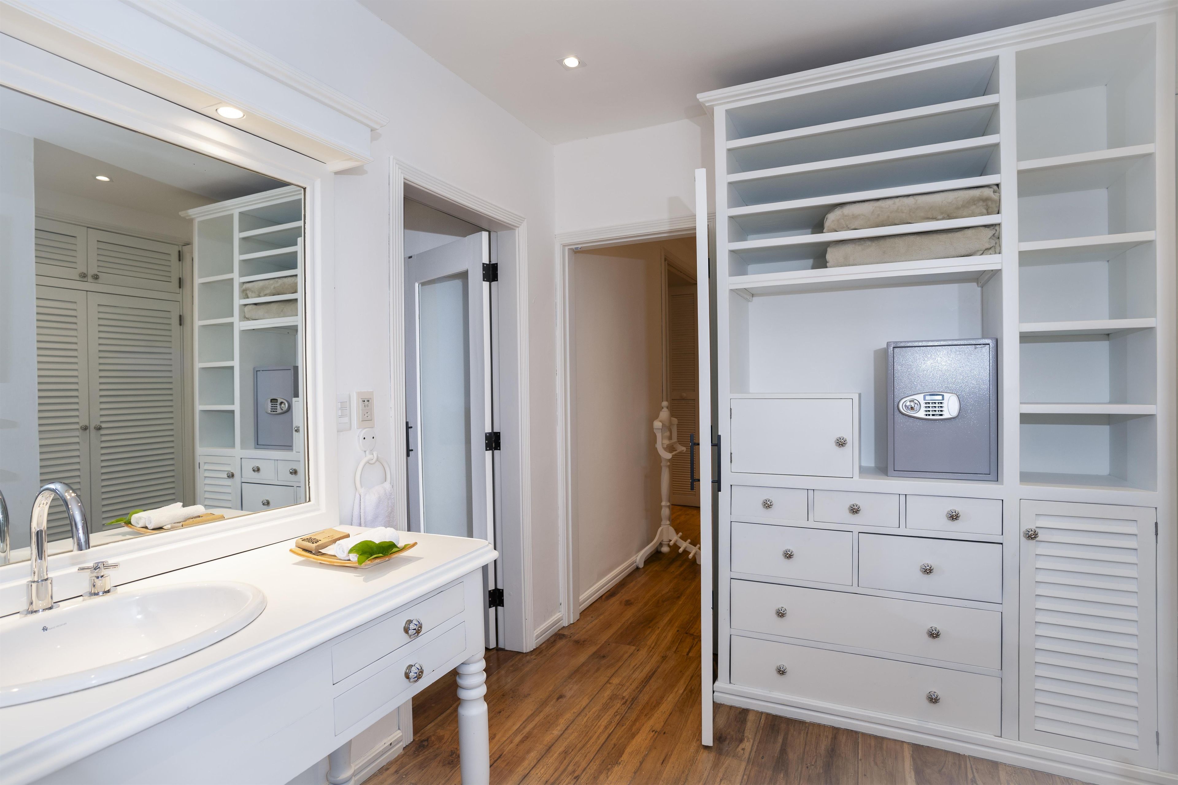 A bathroom with a white vanity, a mirror, a sink, and a towel rack.