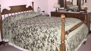 A bedroom with a wooden bed, a dresser, a mirror, and a framed picture on the wall. - A Valley View Bed & Breakfast (Perth South)