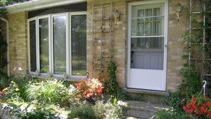 A house with a brick exterior, large windows, and a garden with various plants and flowers. - A Valley View Bed & Breakfast (Perth South)