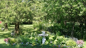 A well-maintained garden with a variety of plants and flowers, a decorative bird sculpture, and a small pond. - A Valley View Bed & Breakfast (Perth South)