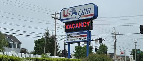 Señal de USA Inn que indica disponibilidad, con servicios que incluyen Wi-Fi, microondas y refrigeradores.