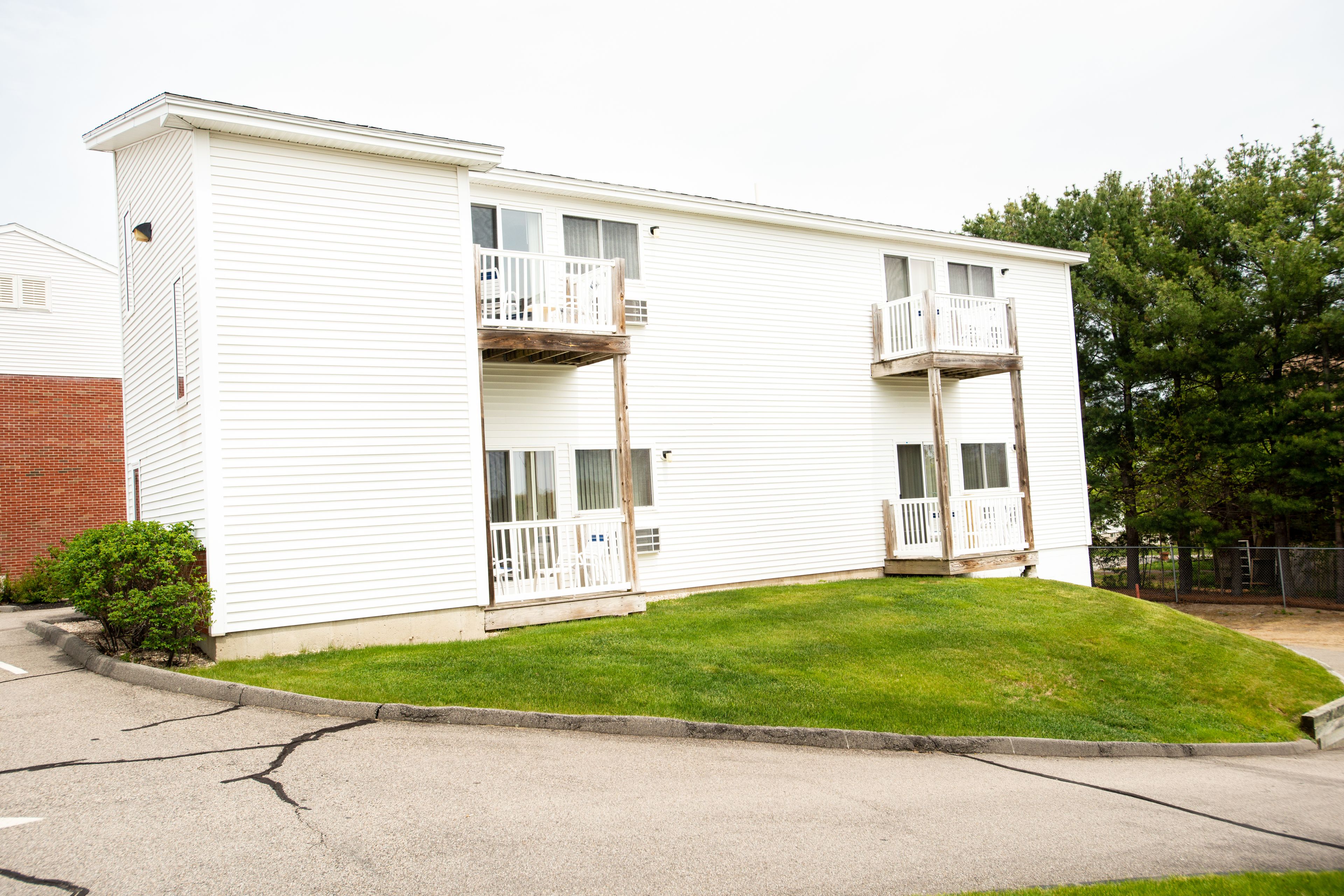 A two-story mobile home with a front porch and a small front yard.