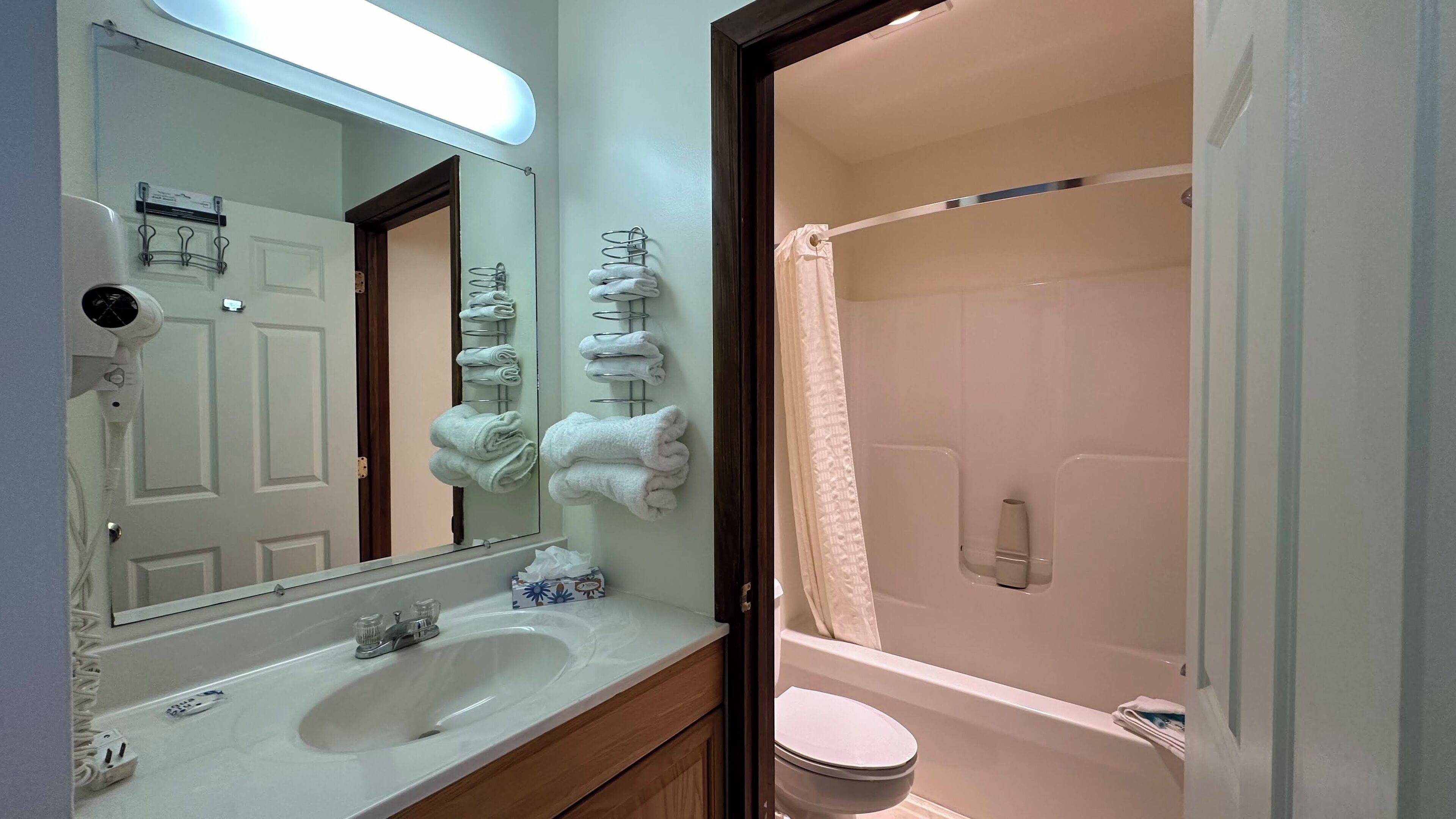 A bathroom with a sink, mirror, towel rack, and a shower area.