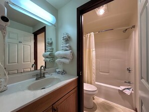 Un baño con lavamanos, espejo, toallero, inodoro y ducha.