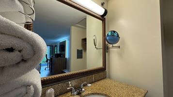 A bathroom with a granite countertop, a white sink, a large mirror, and a towel rack.