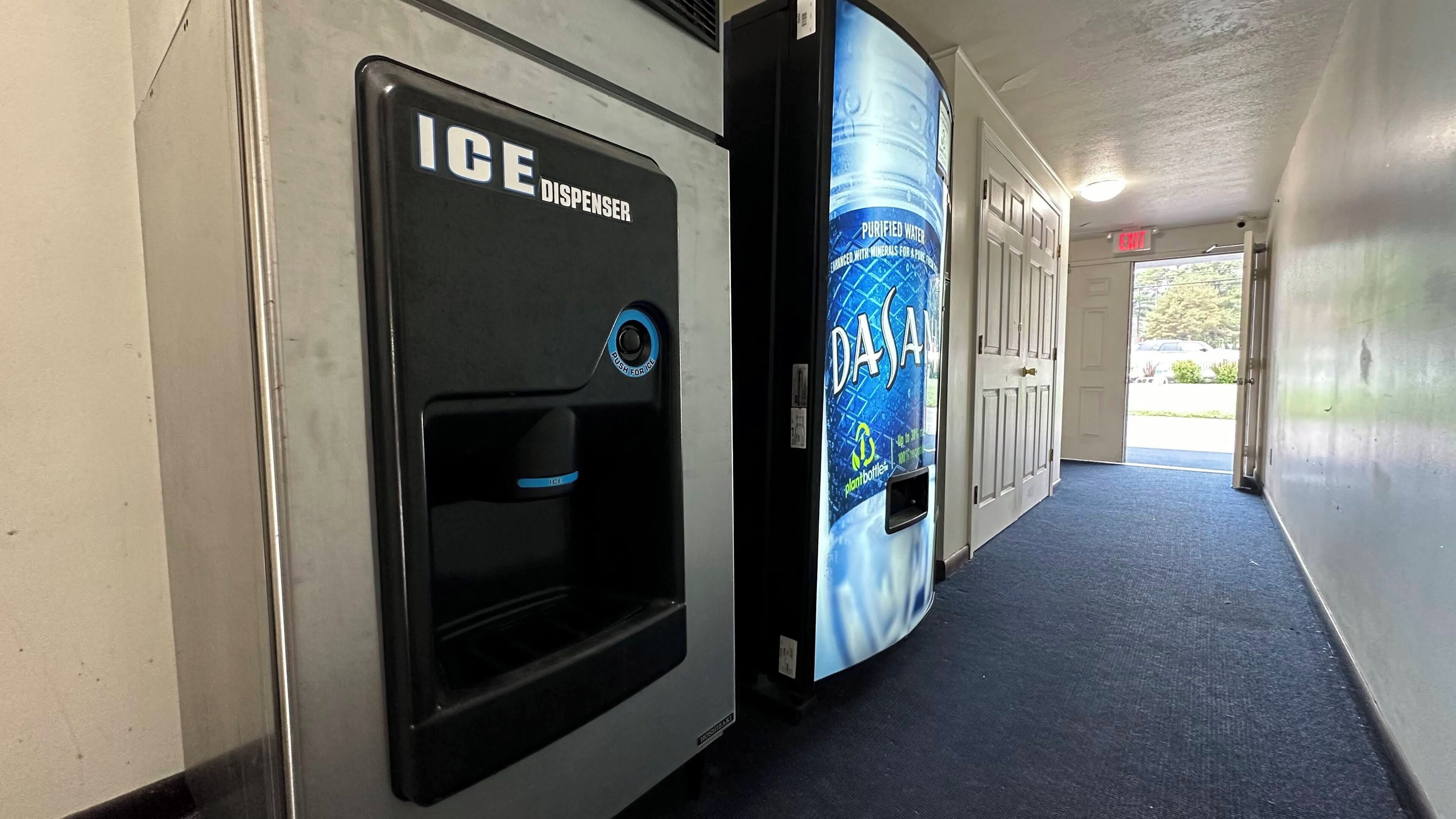 Un distributeur de glaçons et un distributeur d’eau se trouvent dans un couloir dont le sol est recouvert d’une moquette bleue.