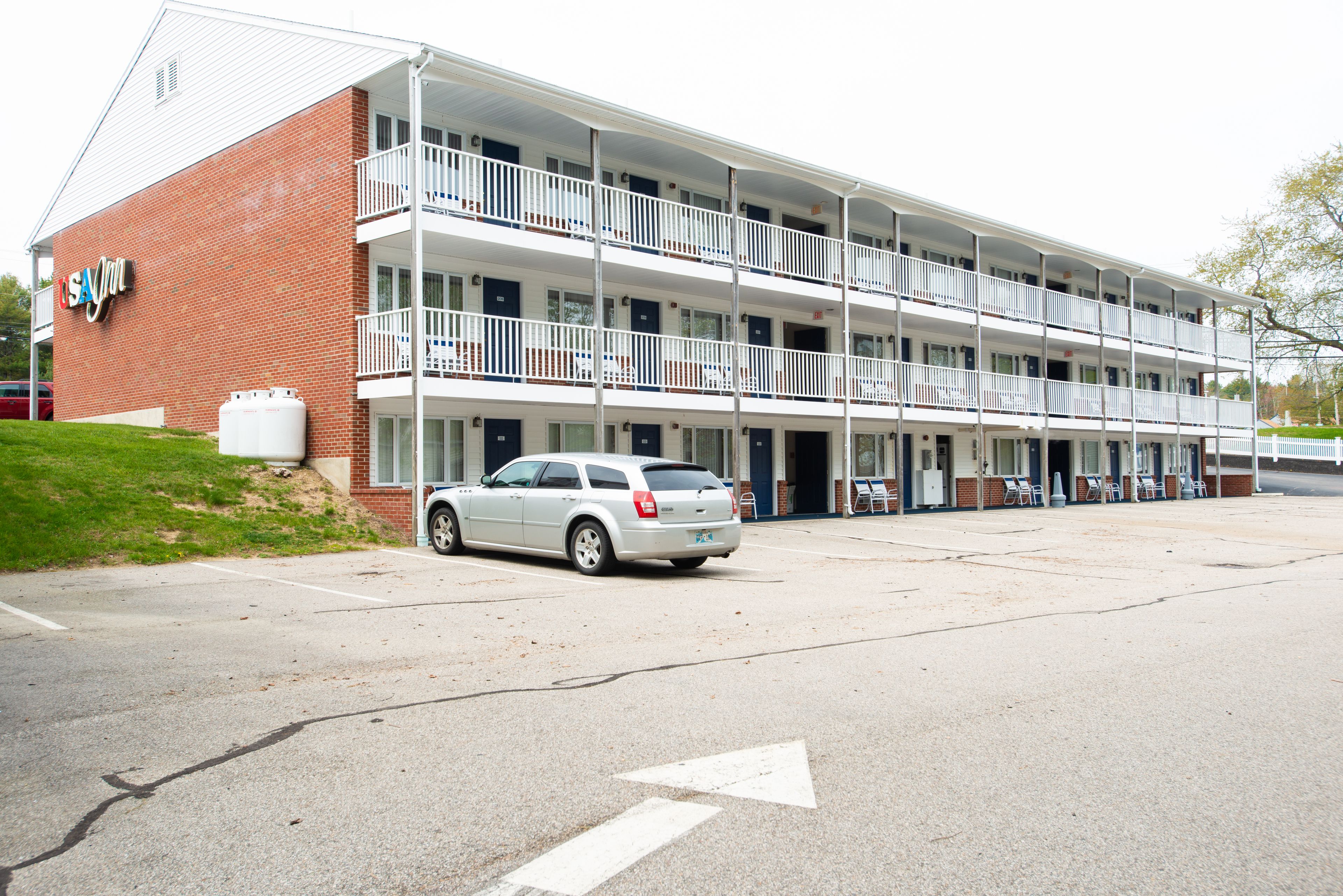 A multi-story motel with a brick facade, multiple balconies, and a parking lot.