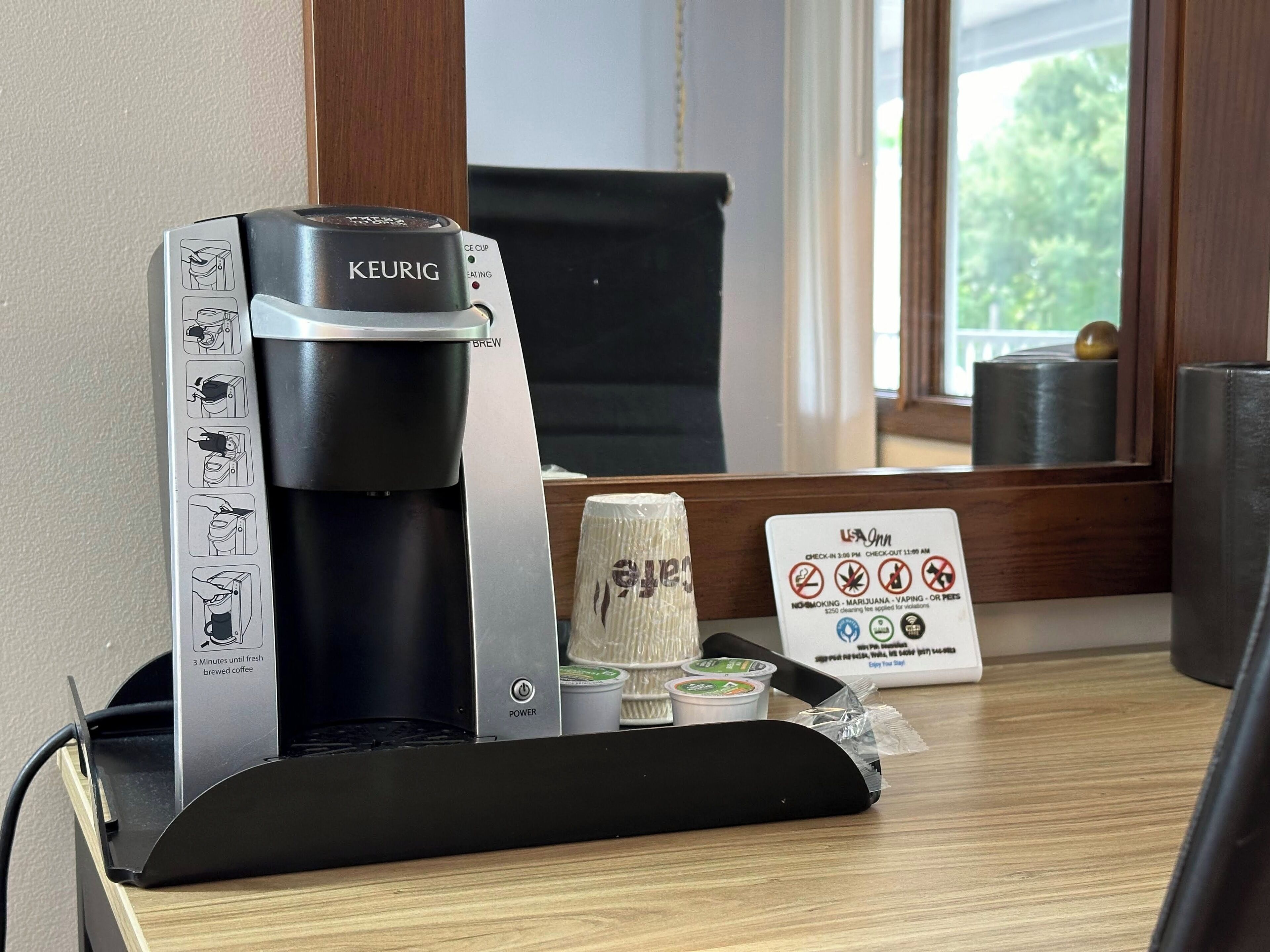 A Keurig coffee machine with instructions, a coffee pod holder, and a sign indicating no smoking, vaping, or pets allowed.