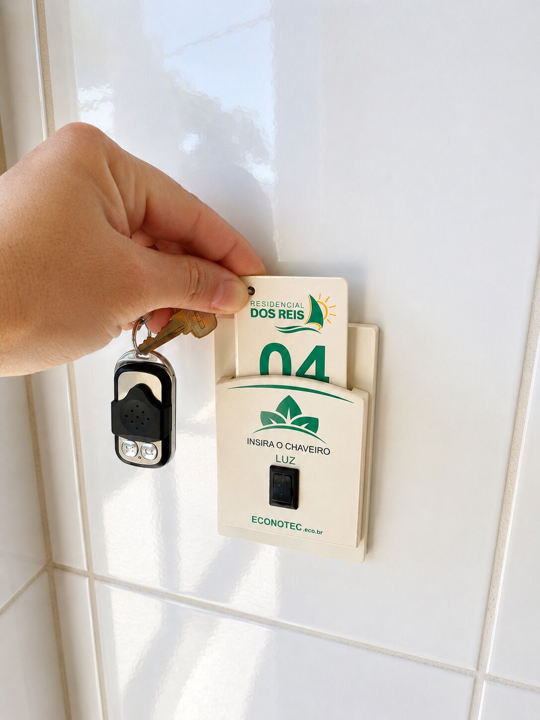 A hand inserting a key into a lock, with a label that reads 'RESIDENCIAL DOS REIS' and 'ECONOTECC.eco.br' on a beige wall.