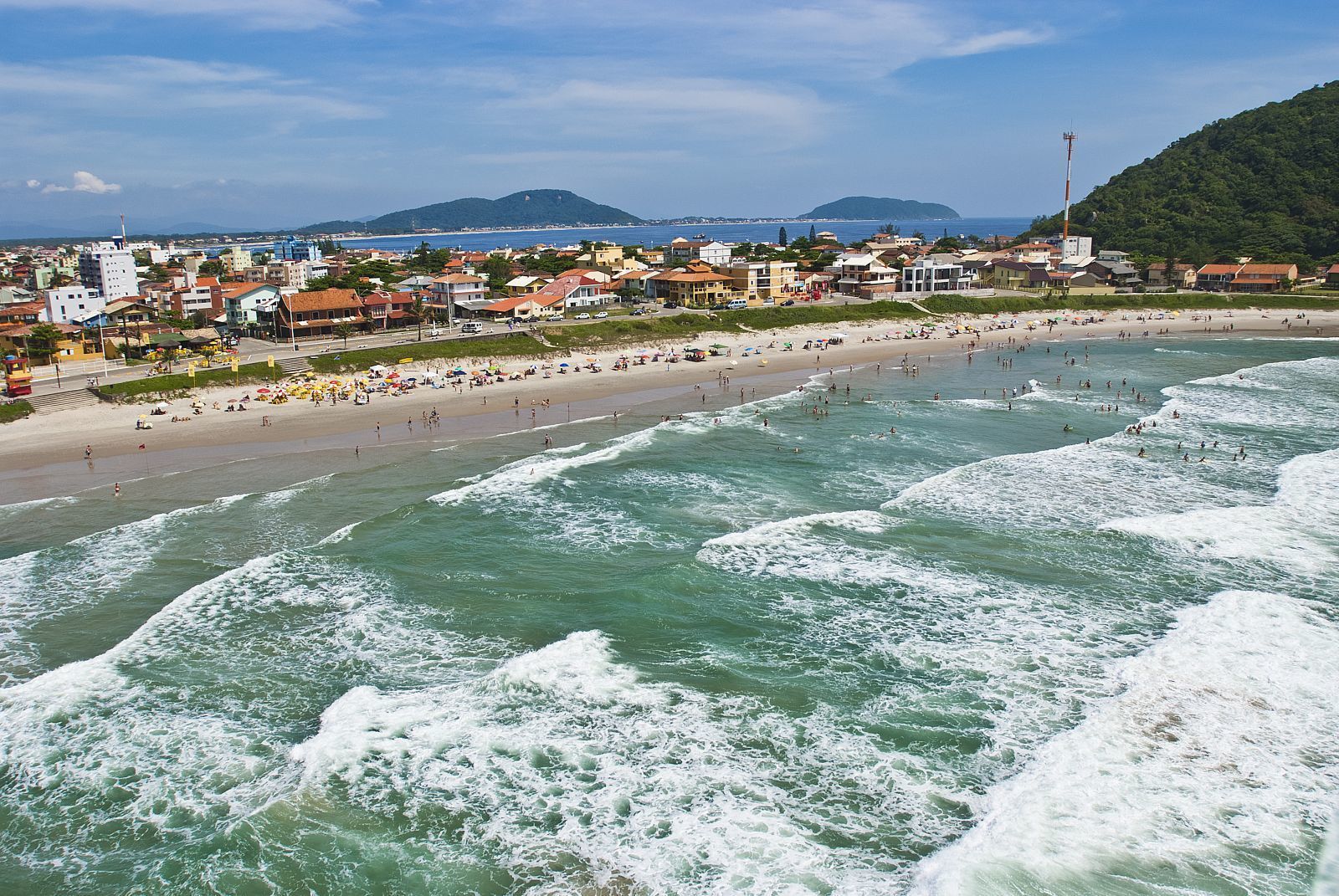 Un pueblo costero con playa, olas y edificios.