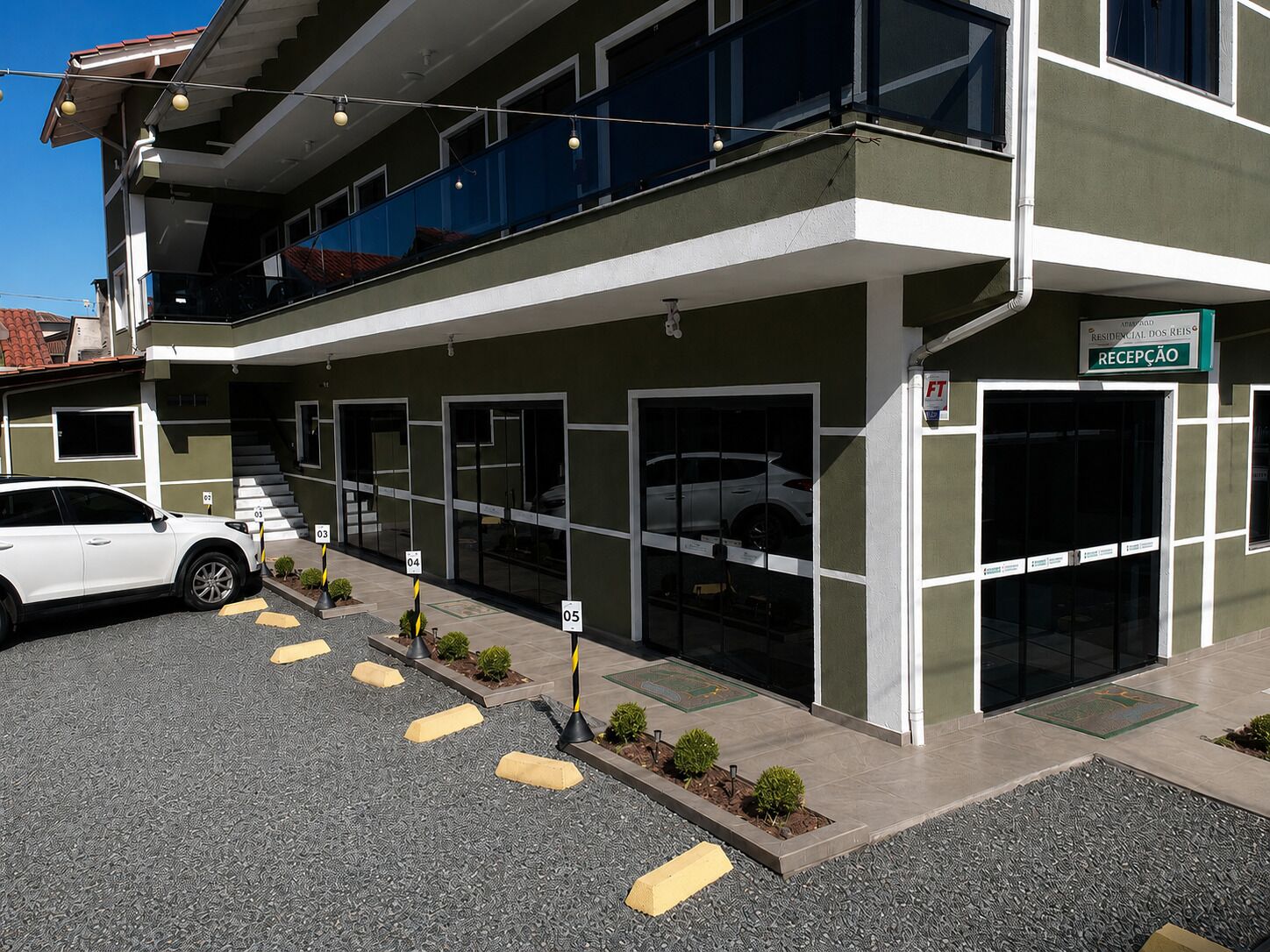 Un bâtiment moderne doté d’un espace d’accueil, de nombreux emplacements de stationnement et d’une voiture blanche garée devant.