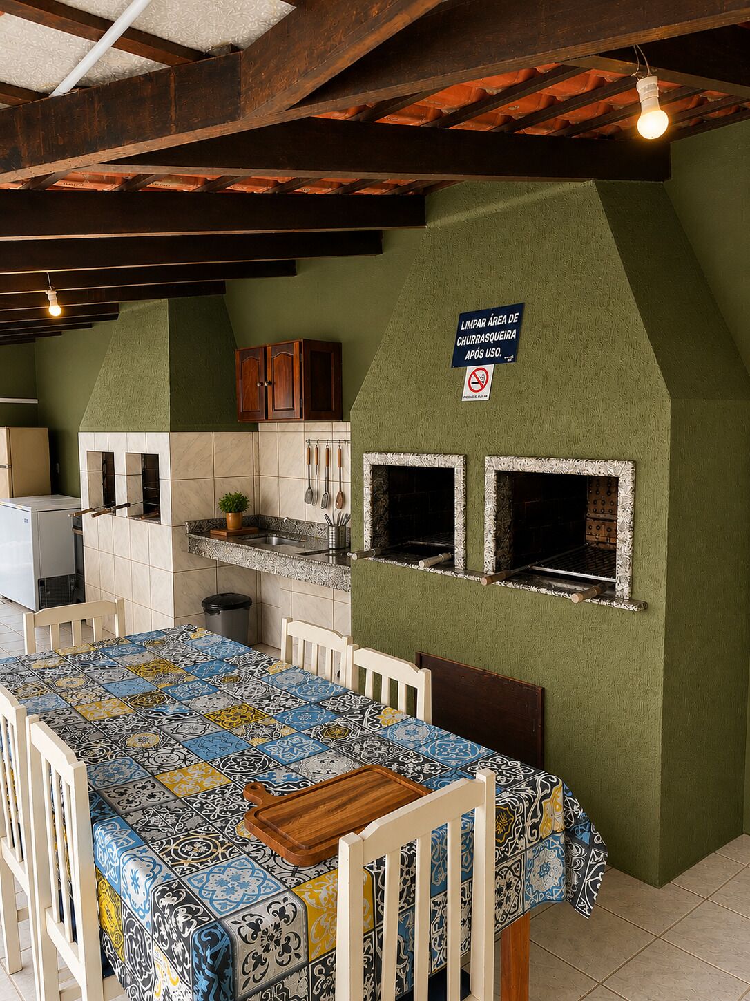 A kitchen with a tiled backsplash, a wooden table with a colorful tablecloth, and two built-in ovens.
