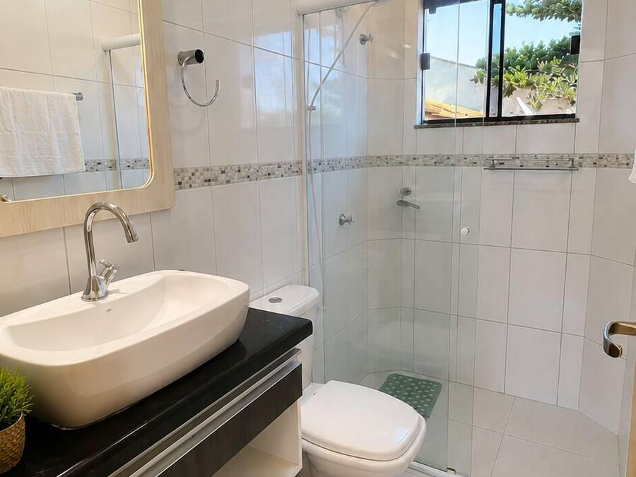 A modern bathroom with a large sink, toilet, and glass shower enclosure.