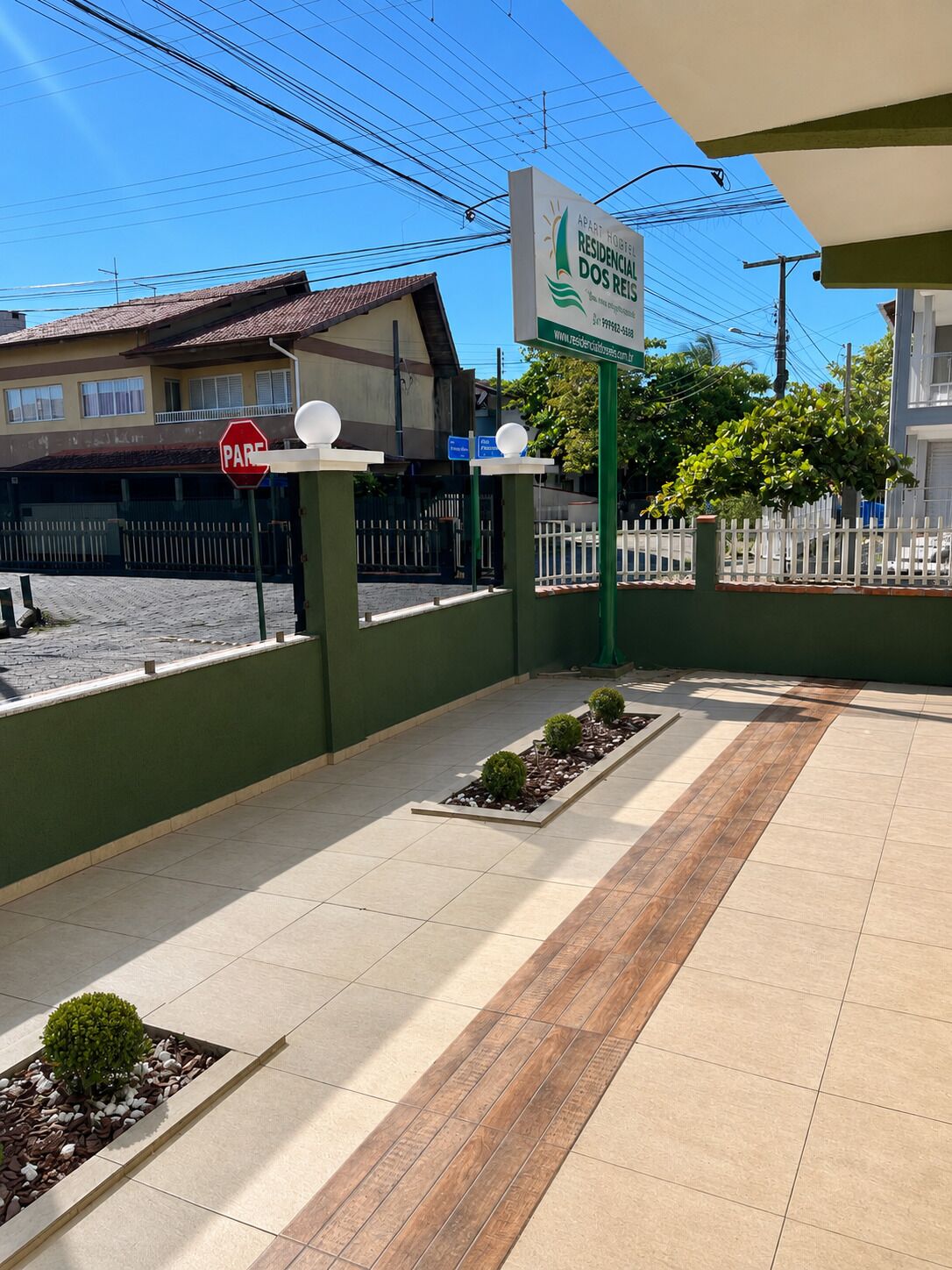 A residential building with a sign indicating 'APART HOBITO RESIDENCIAL DOS REIS' and a 'PARE' sign.