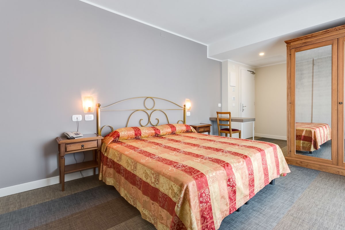 A bedroom with a bed, bedside table, lamp, and a wardrobe.