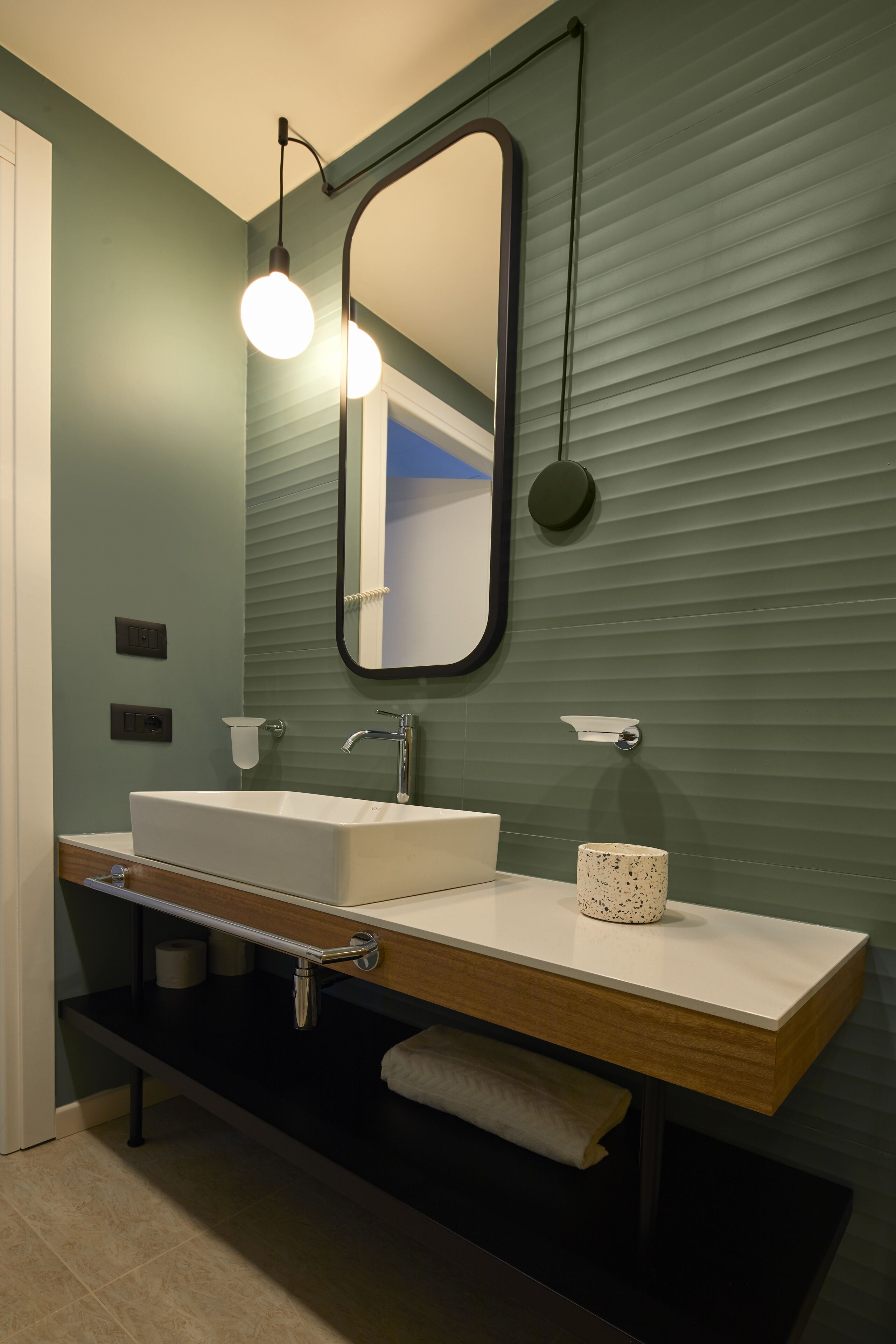 A modern bathroom with a rectangular sink, a mirror, and a towel rack.